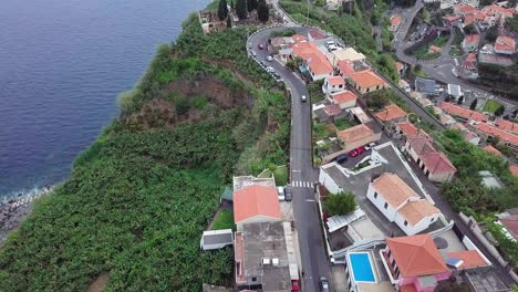 Küstenhäuser-Und-Straßen,-Die-Auf-Dem-üppigen-Hochland-Der-Vulkanischen-Insel-Madeira,-Portugal,-Gebaut-Wurden---Luftdrohne