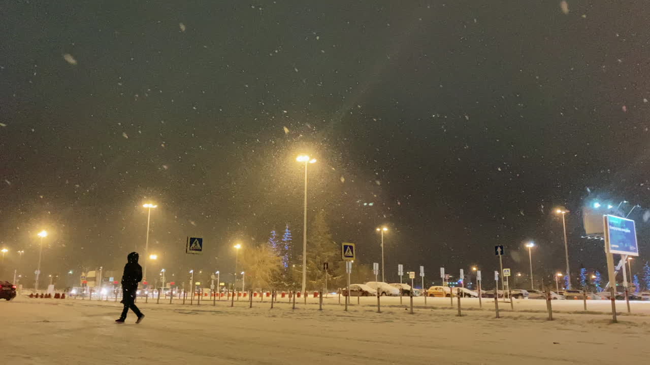 Snowy night parking lot with a person walking