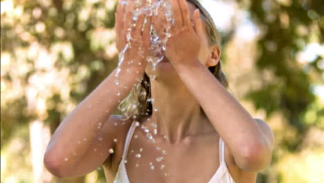 blonde woman splashing herself in slow motion