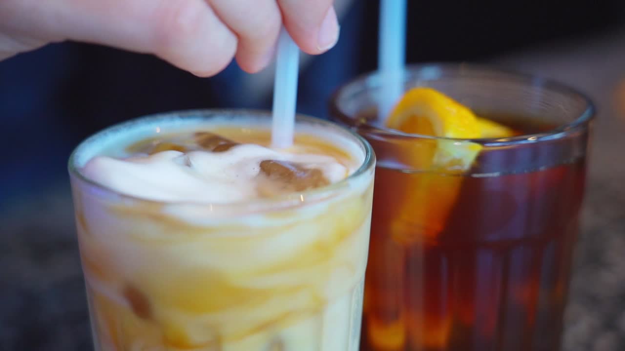 Close-up of iced latte and iced tea with visible ice and orange slices