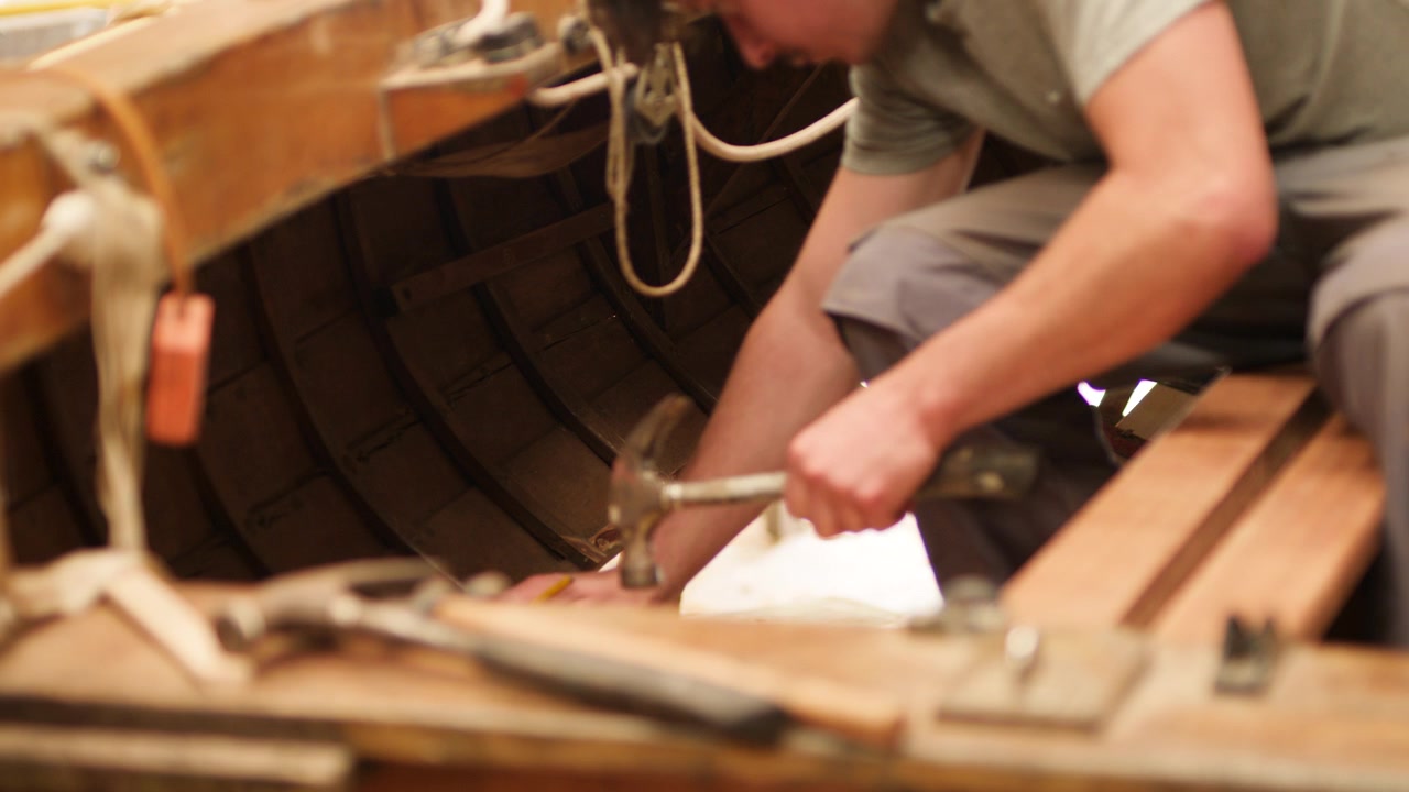 Carpenter working restoring old wood boat hull planks
