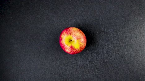 red apple slowly rotating in place against a clean black background for isolated product use, top down