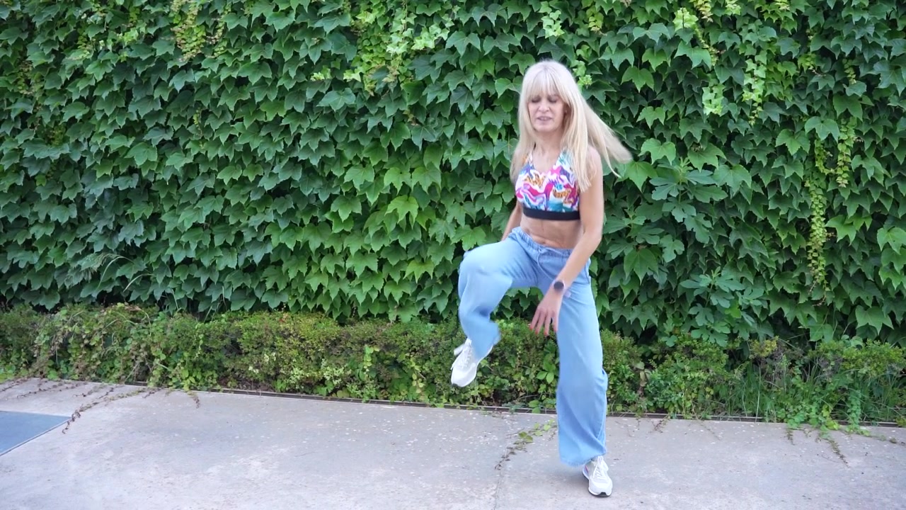 Engage in a lively outdoor dance session with a woman sporting a floral top and jeans