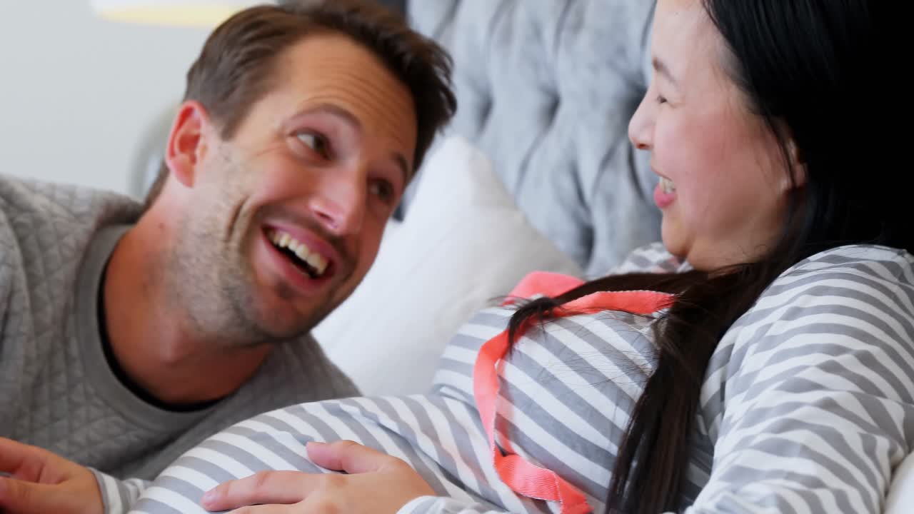 Man and pregnant woman discussing over sonography in bedroom 4k