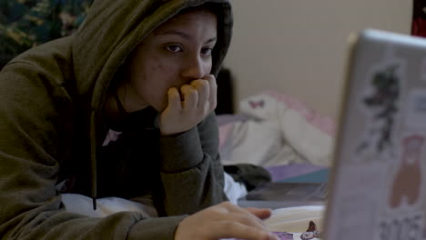 teenage girl using laptop in bedroom