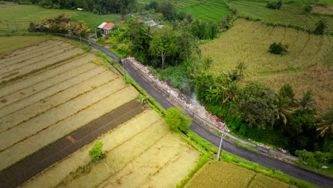 Vista-Aérea-Superior-De-La-Pila-De-Basura-Humeante-Arrojada-Al-Costado-De-La-Carretera-Rural-De-Bali