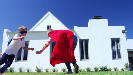 mother and son in superhero costume having fun in garden 4k