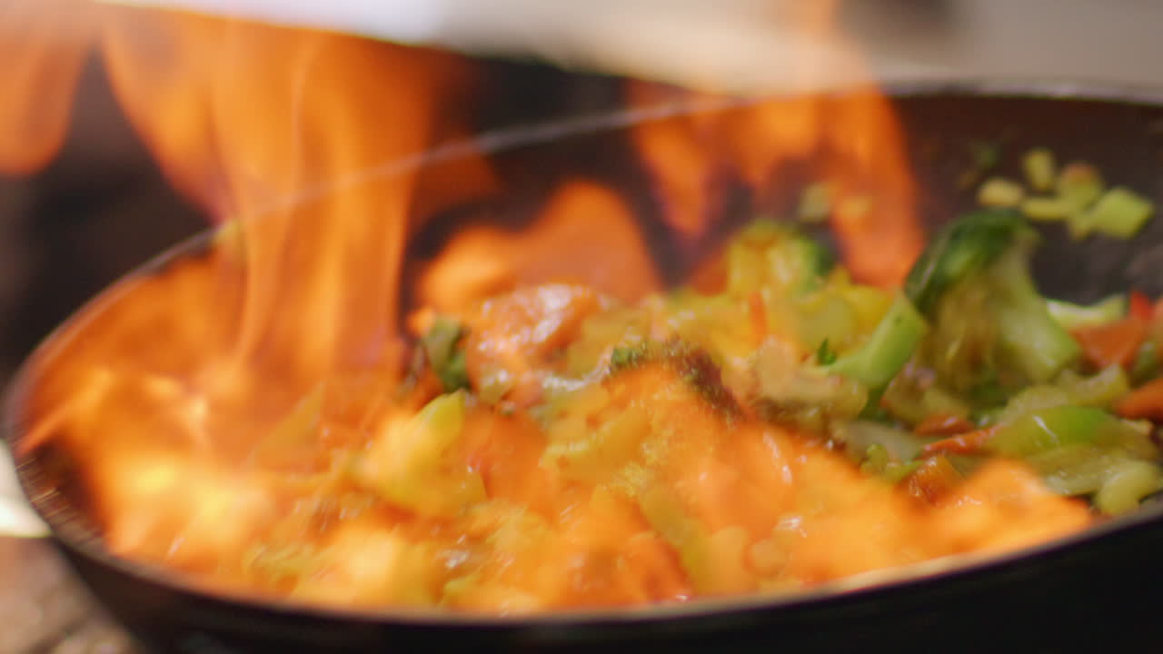 Primo piano di verdure flambé saltate in padella con fiamme alte
