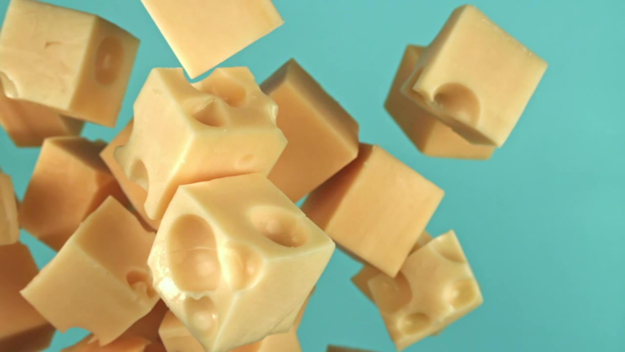 Cubetti di formaggio che cadono al rallentatore su sfondo blu