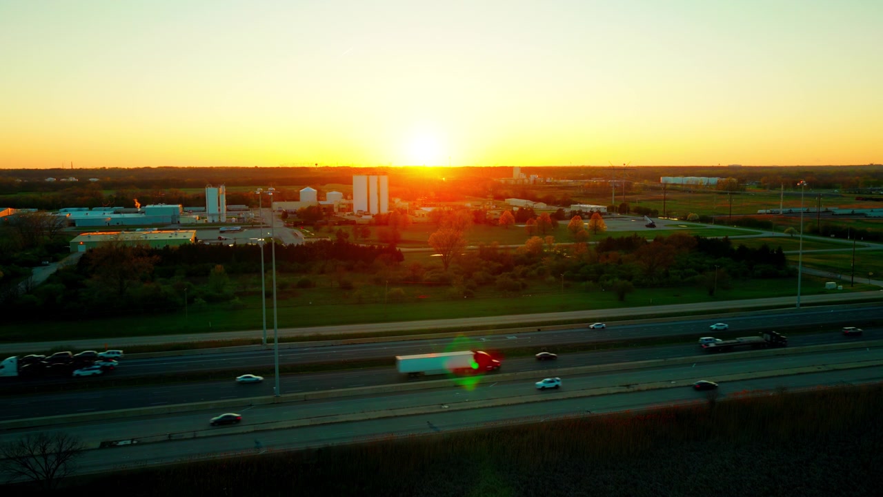 Bisarche cariche e autoarticolati che viaggiano sulla Interstate 55 al tramonto vicino a Channahon, Illinois, trasportando veicoli impilati attraverso il Midwest