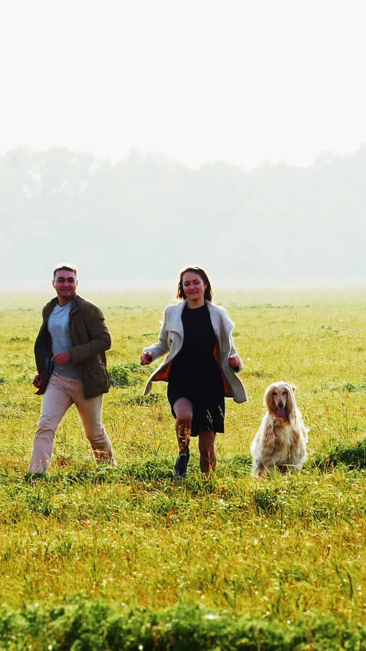 Couple and Dog Running in a Field