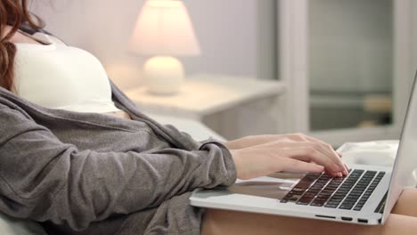 woman hands typing laptop keyboard in bed. female hands typing keyboard