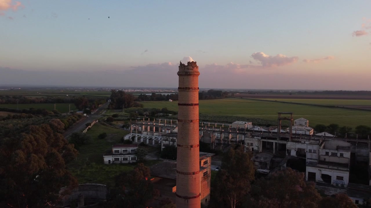 Drone kredser om et tårn i en stor forladt fabrik ved solnedgang, Sevilla, Spanien