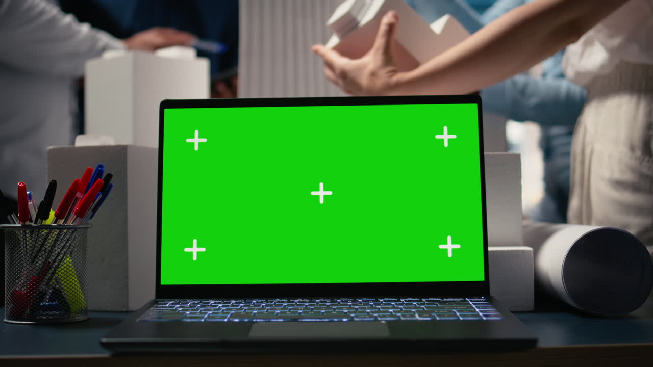 Real estate experts analyzing blueprints and models next to green screen