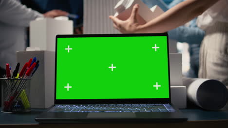 real estate experts analyzing blueprints and models next to green screen