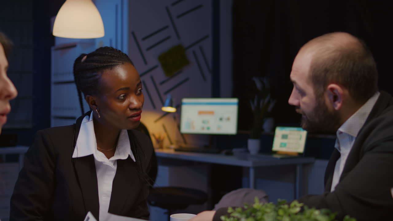 Diverse multiethnic businesspeople sharing management graphs paperwork overworking in office meeting room