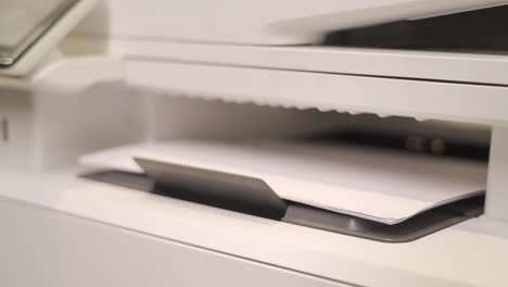 The-office-printer-is-working,-white-sheets-come-out-of-the-printer,-close-up