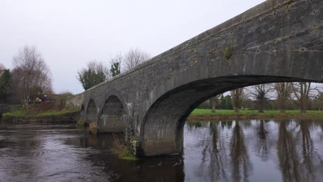 puente histórico sobre el río con agua corriente en atti kildare, irlanda