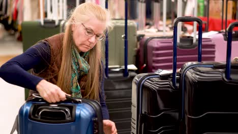 Closeup of blonde, mature woman shopping for luggage in a retail store