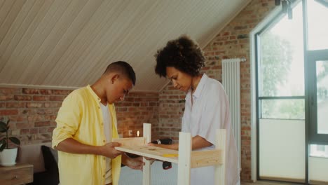 mother and son assembling wooden shelving unit