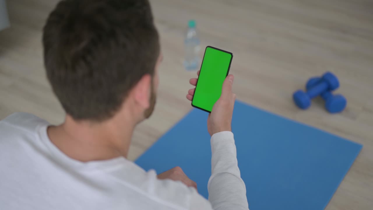 Rear View of Man using Smartphone with Chroma Key Screen on Yoga Mat