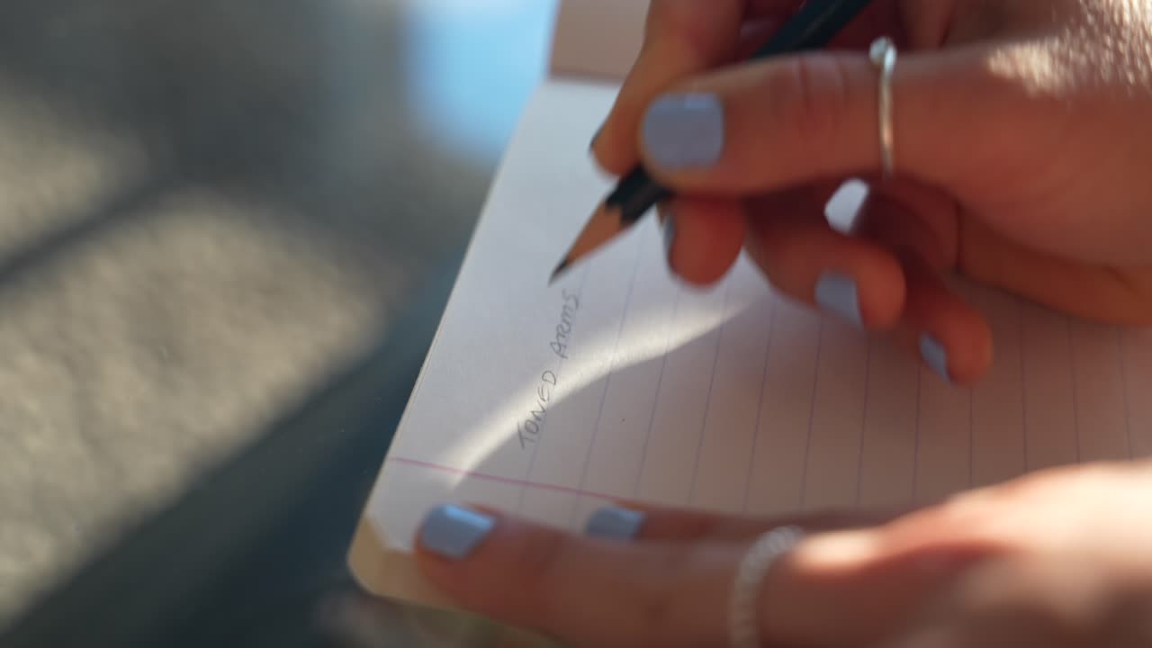 Close-up of female handwriting notes with pencil. Woman working from home