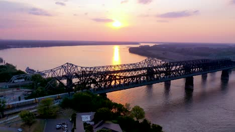 aerial of landmark three steel bridges over the mississippi river at sunset with memphis tennessee background