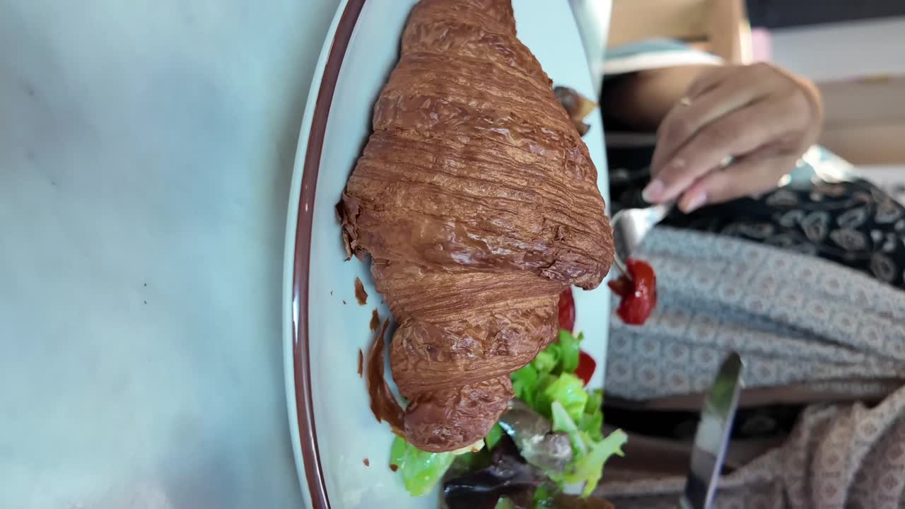 Enjoying a flaky croissant and salad for breakfast