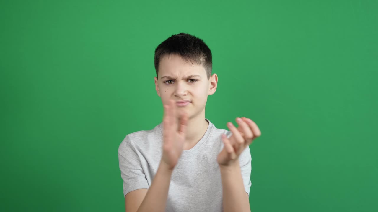 화를 내고 불만을 품은 회의적인 십대가 녹색 화면 배경에서 손을 치고 있습니다.
