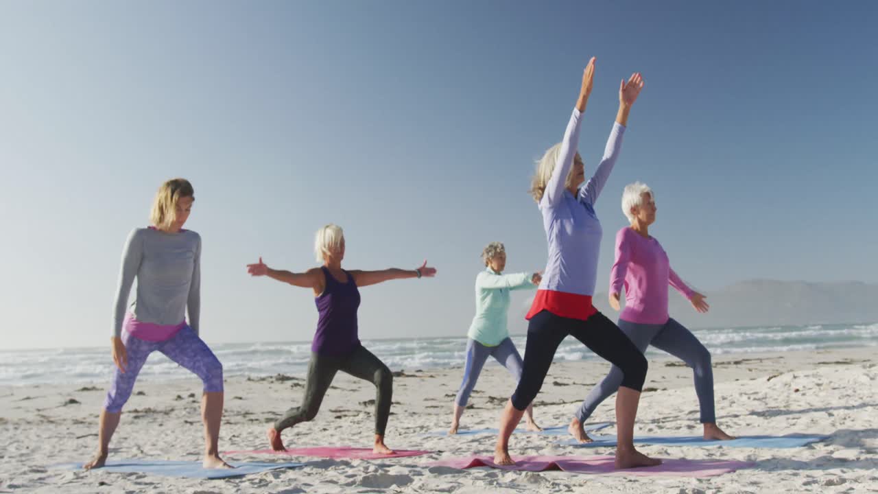 Athletic women performing yoga in the beach