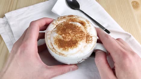 cappuccino or latte. two hands hold cup with milk froth