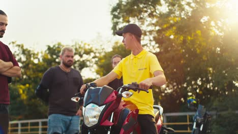 Ein-Fahrlehrer-Im-Gelben-T-Shirt-Erklärt-Seinen-Schülern,-Wie-Man-Auf-Einem-Motorrad-Sitzt-Und-Es-Richtig-Fährt.-Unterricht-Auf-Dem-Gelände-Einer-Motorradschule-Bei-Sonnigem-Wetter