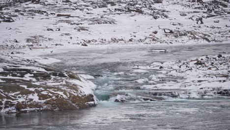 Waterfall-flowing-through-snowy-river