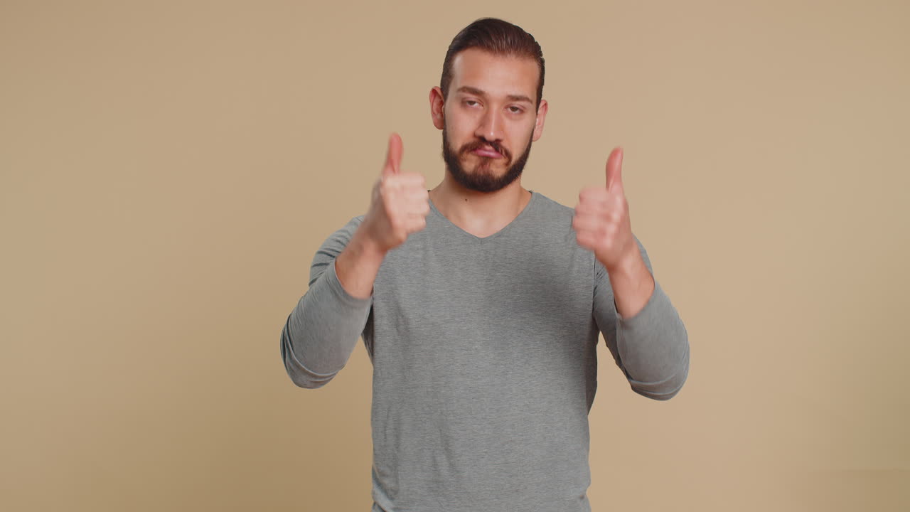 Young man showing thumbs up and nodding in approval claps hands successful nice work good job