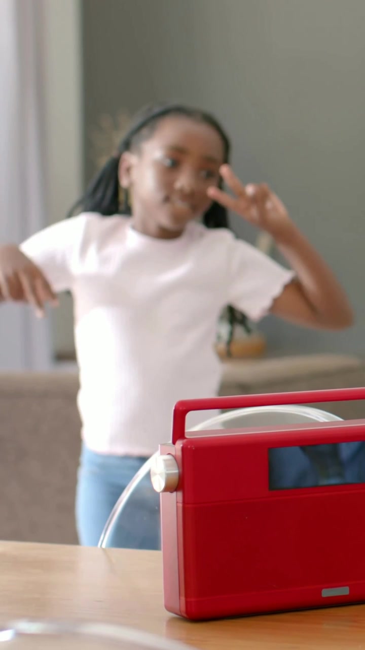Vertical video: Starting girl in pink top dancing to red radio with tube doing peace signs at home