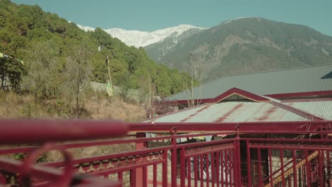 red bridge with mountain view in the background, sunny day, serene atmosphere, outdoor shot