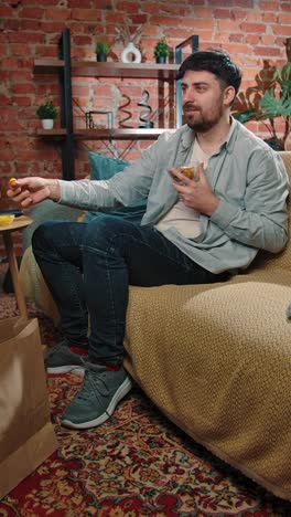 man relaxing on couch with snacks