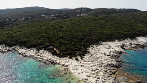 Hermosa-Playa-Pedregosa-Y-Exuberantes-Colinas-Verdes-De-Paralia-Emplisi-En-Erisos-Grecia--Zoom-Aéreo-En-Toma