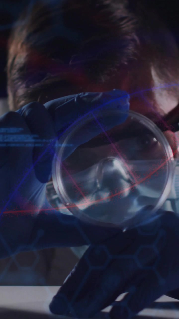Video verticale: Tecnico di laboratorio che solleva una capsula di Petri e analizza un campione al banco, con sovrapposizioni di guanti, occhiali e maschera