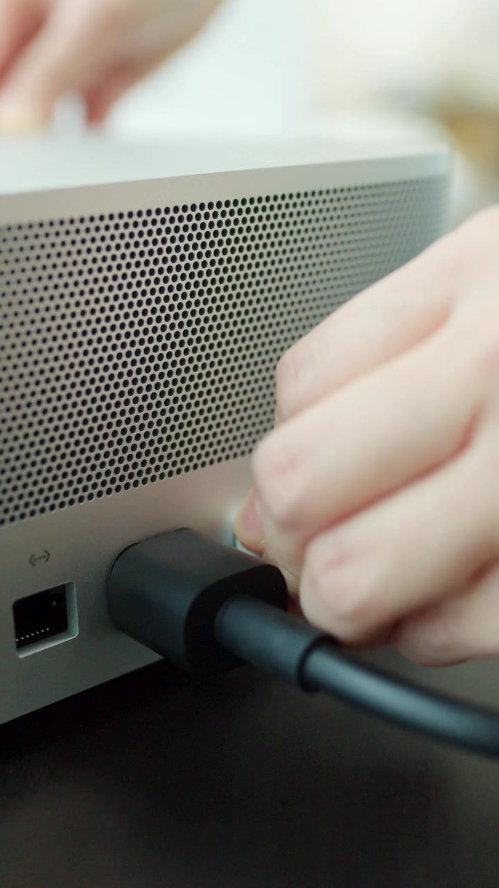 Primo piano di una persona che collega un cavo USB a un computer desktop su una scrivania scura, con luce naturale soffusa.