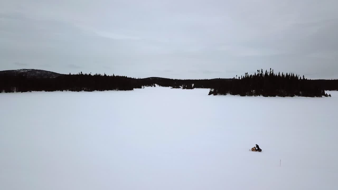 toma aérea de un jinete de motos de nieve solo en la inmensidad de un lago congelado en chibougamau, quebec