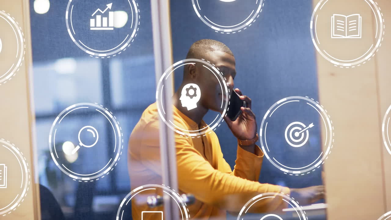 Animation of media icons over african american casual businessman talking on smartphone in office