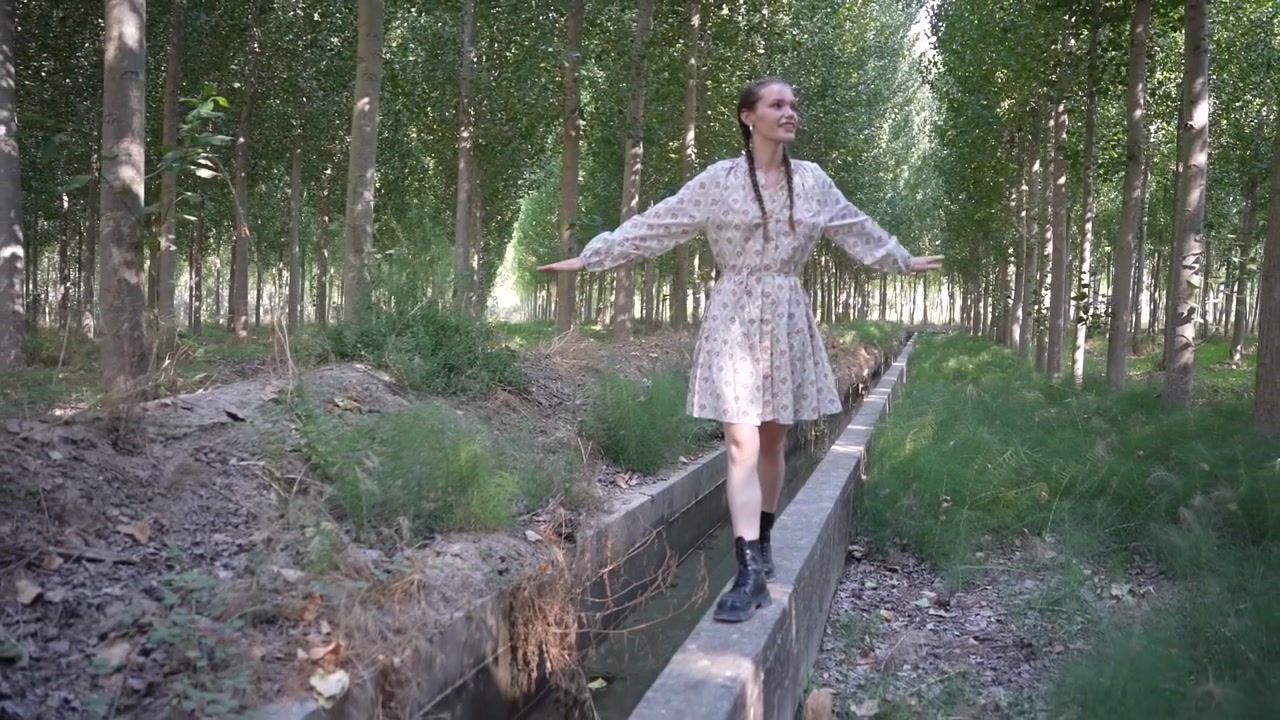 Una donna serena che cammina con grazia lungo un tranquillo sentiero nel bosco, circondata dalla natura.