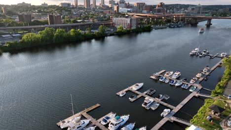 albany yacht club with swimming pool with river and downtown of albany in background, new york. aerisl tilt up wide shot. skyline with skyscraper lighting at golden hour