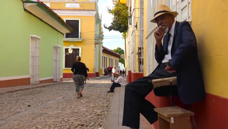 a cuban man smokes a cigar on the colorful streets of trinidad cuba 1