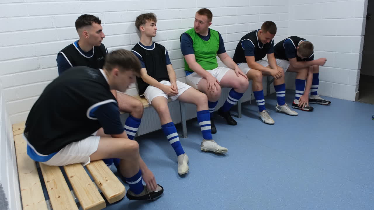 Soccer team preparing in locker room, tying shoes and discussing strategy