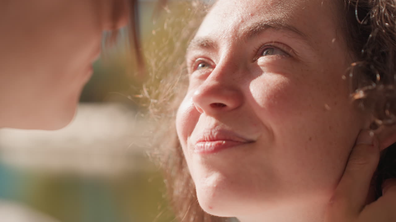 Caucasian woman smiling up at partner by lake sunlight, young poet and partner share quiet affectionate moment after kiss, gentle hand at nape, hopeful gaze toward future family and marriage plans