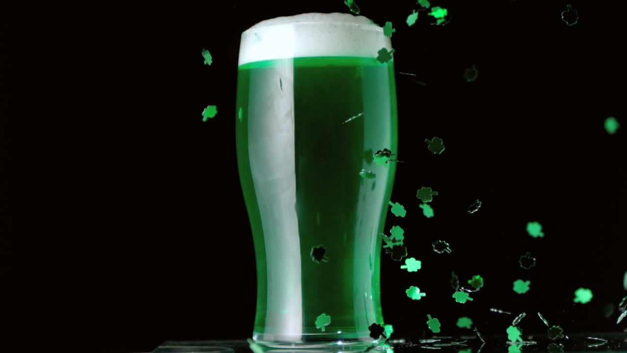 Shamrock confetti falling in front of pint of green beer