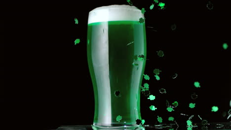 shamrock confetti falling in front of pint of green beer