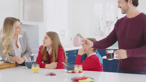 parents helping children in school uniform get ready as they eat breakfast at kitchen counter